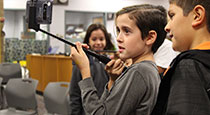 Students holding up a phone on a selfie stick.