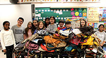 Students standing in front of handbags.